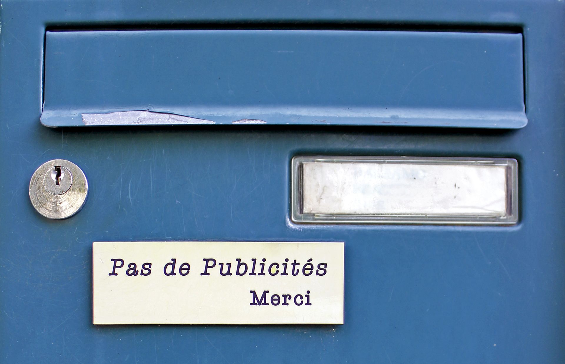 Une boîte aux lettres bleue avec une étiquette indiquant « pas de publicités merci »