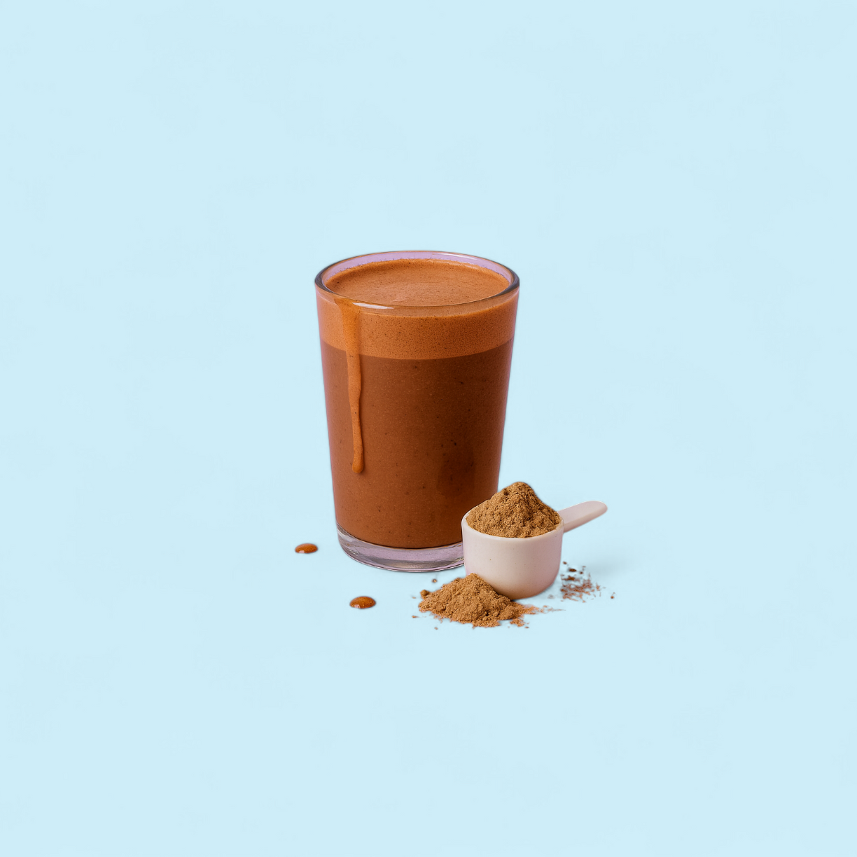 Glass of brown protein shake with a scoop of powder on a blue background.