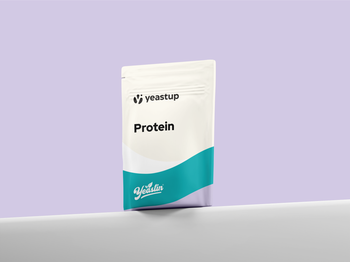 White and teal protein powder packet on a white surface against a purple background; brand logo visible.
