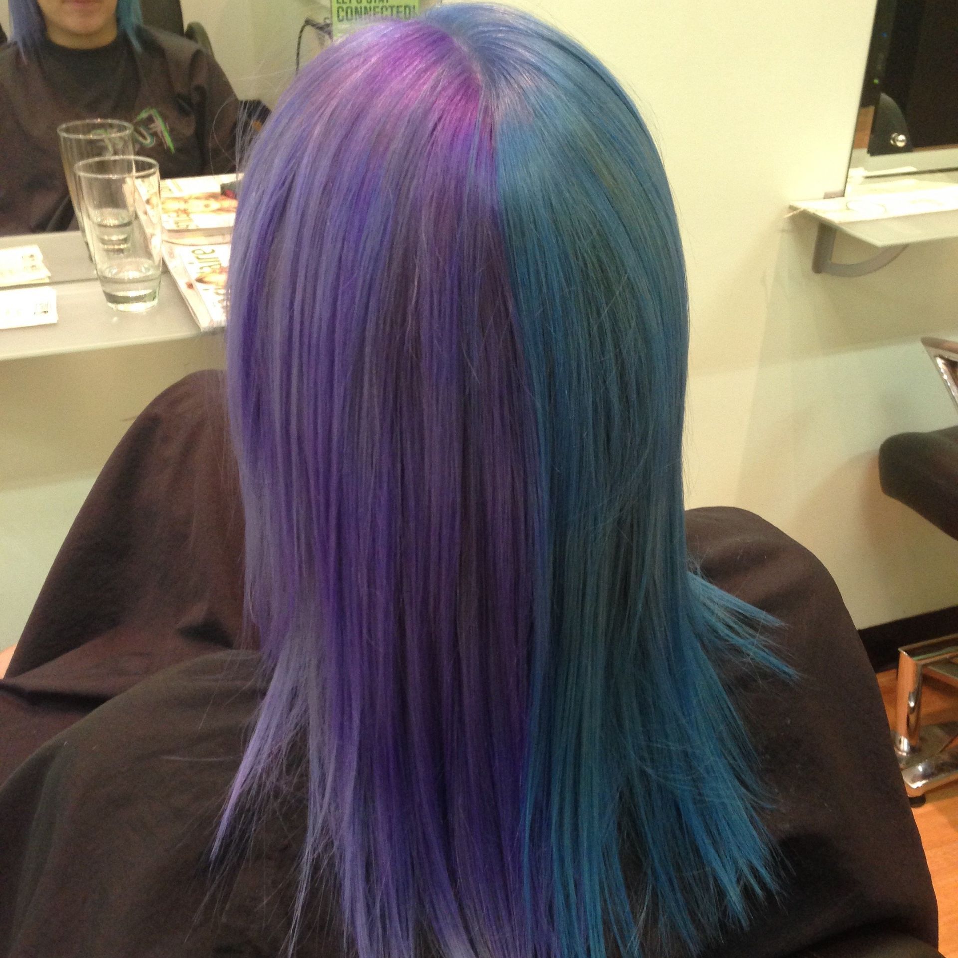 A woman with blue and purple hair is sitting in a chair