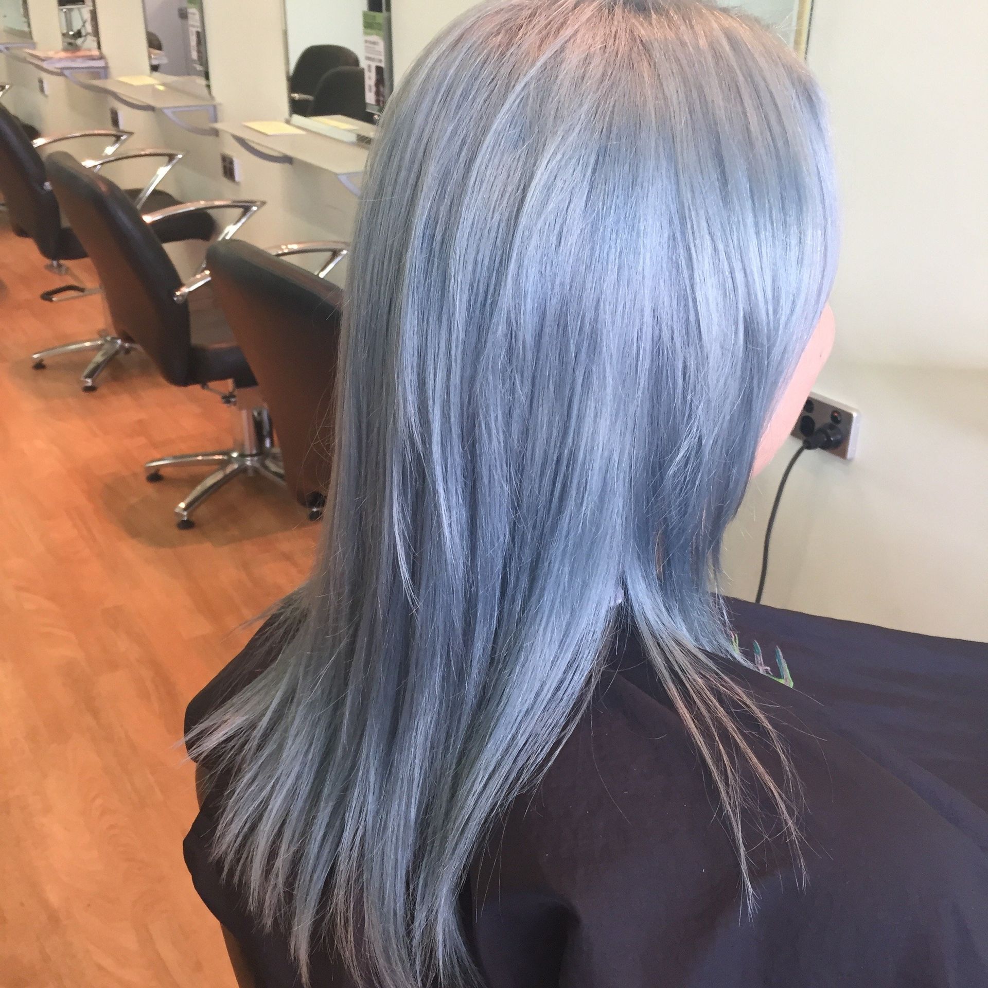 A woman with blue hair is sitting in a hair salon