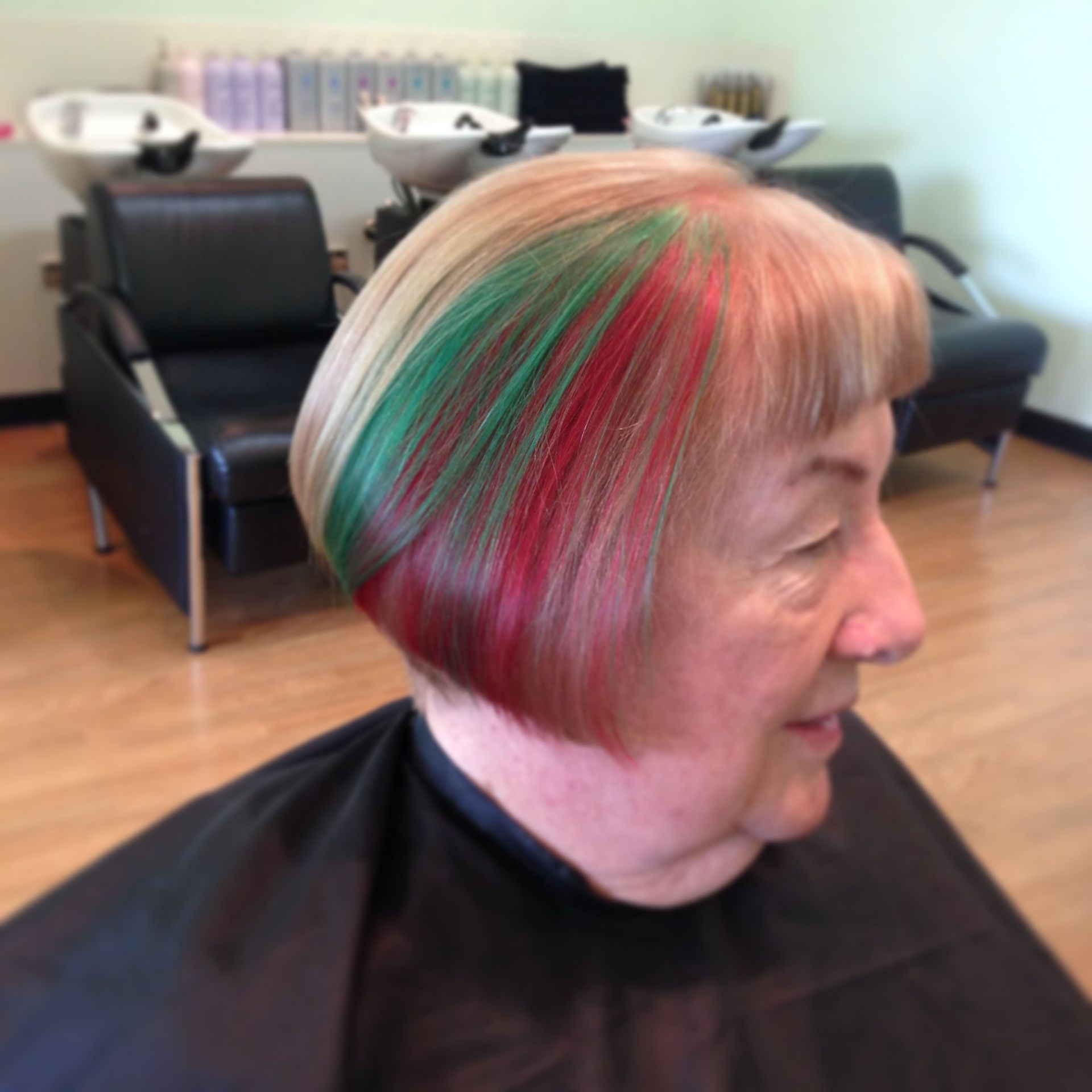 A woman with red and green hair is sitting in a chair