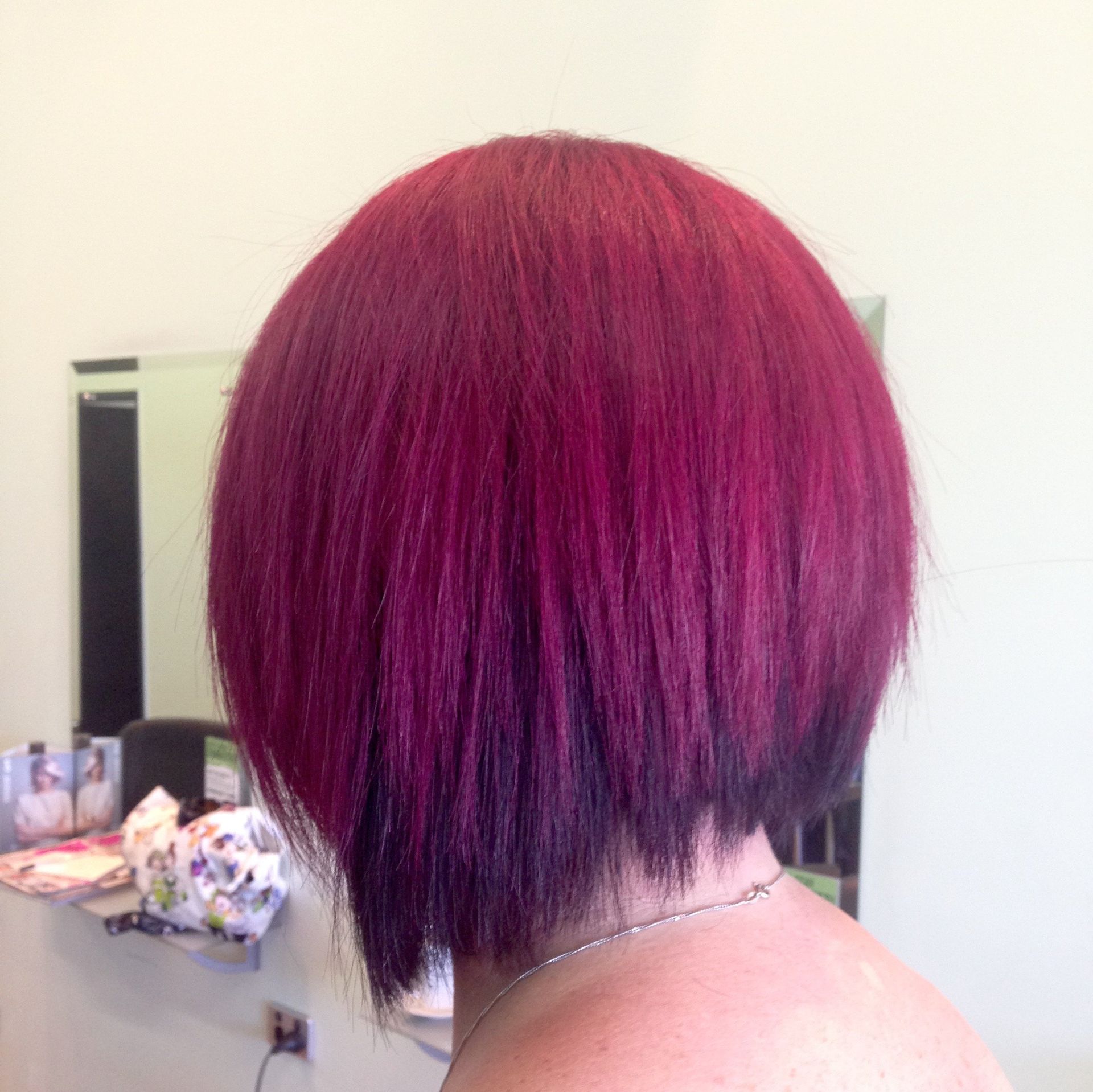 A woman with red hair is standing in front of a mirror