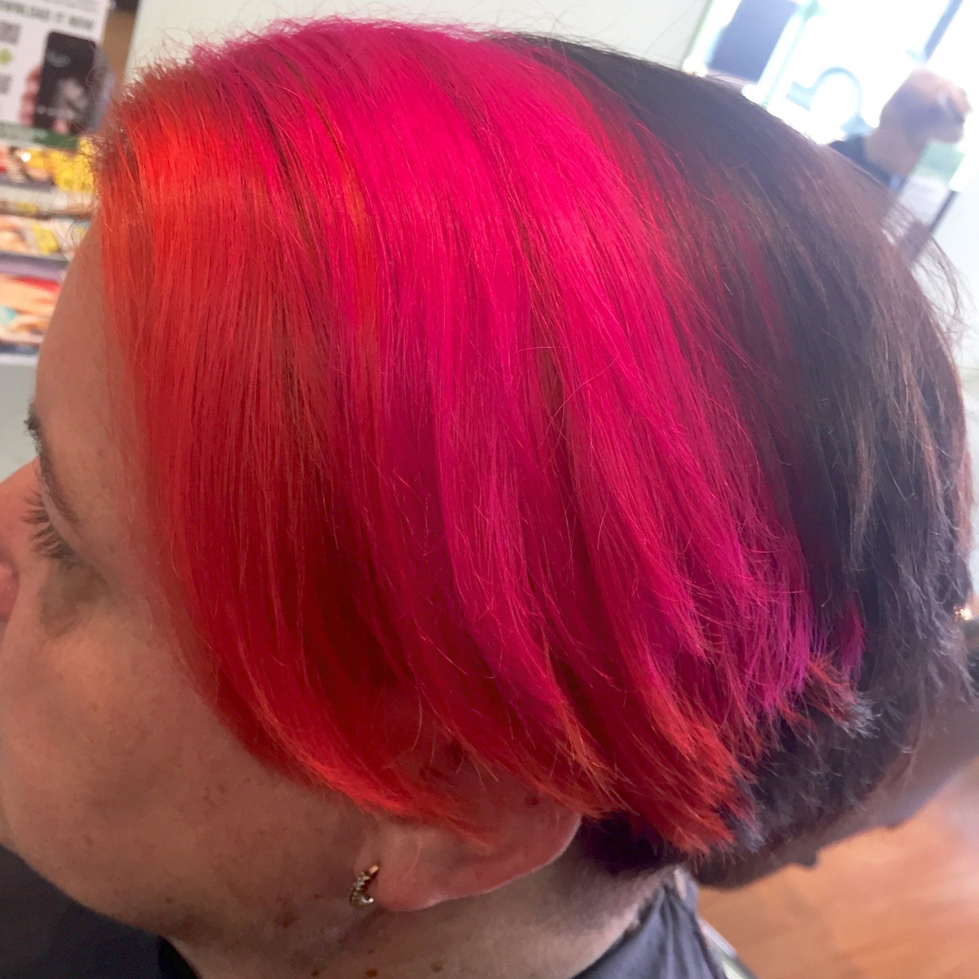 A woman with red hair is getting her hair dyed in a salon.
