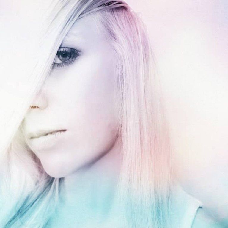 A close up of a woman 's face with a rainbow hair color.