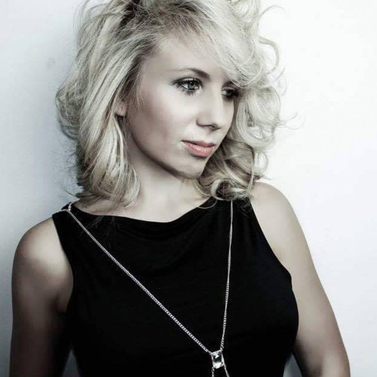 A blonde woman wearing a black dress and a necklace
