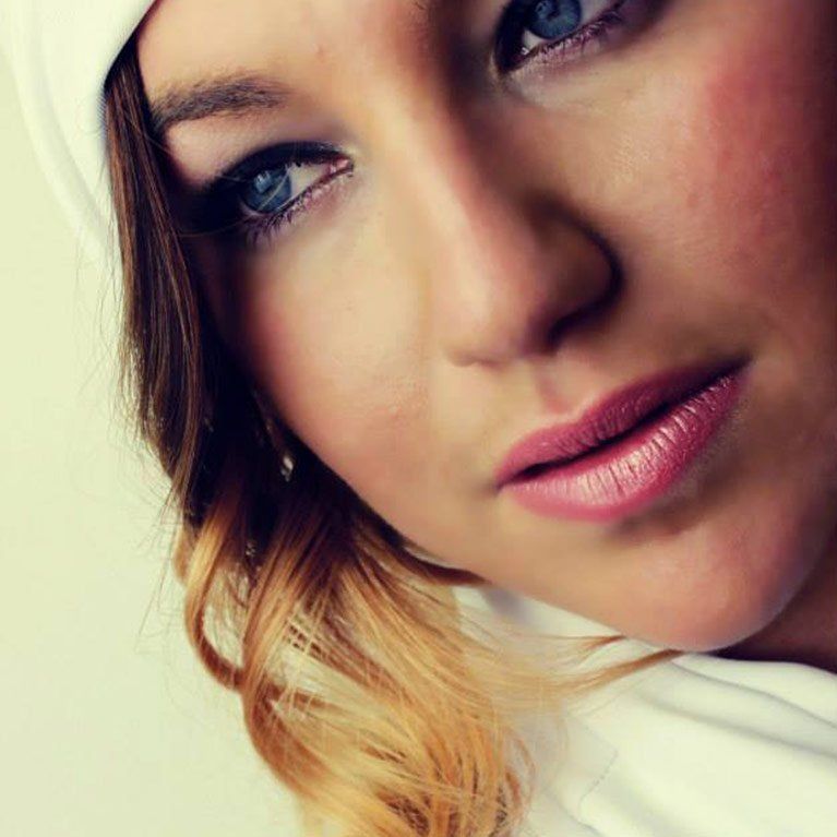 A close up of a woman 's face wearing a white hat