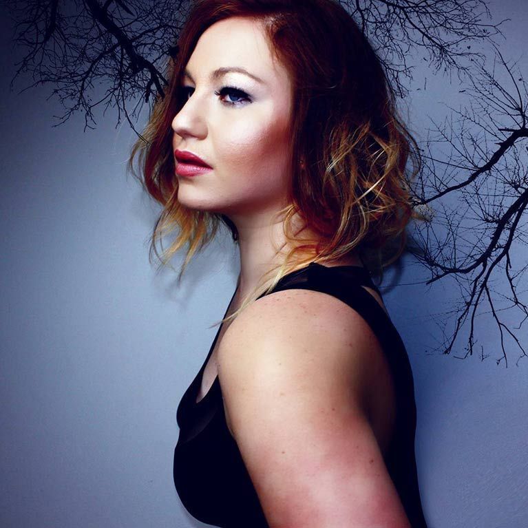 A woman with red hair is wearing a black tank top