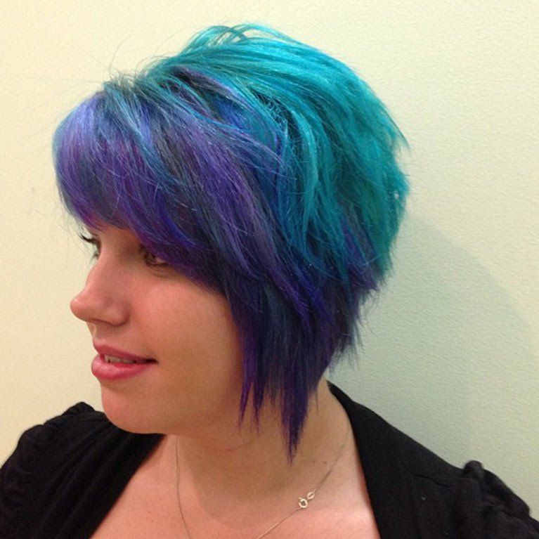 A woman with blue and purple hair is wearing a necklace
