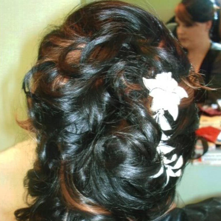 A woman 's hair is in a bun with a flower in it