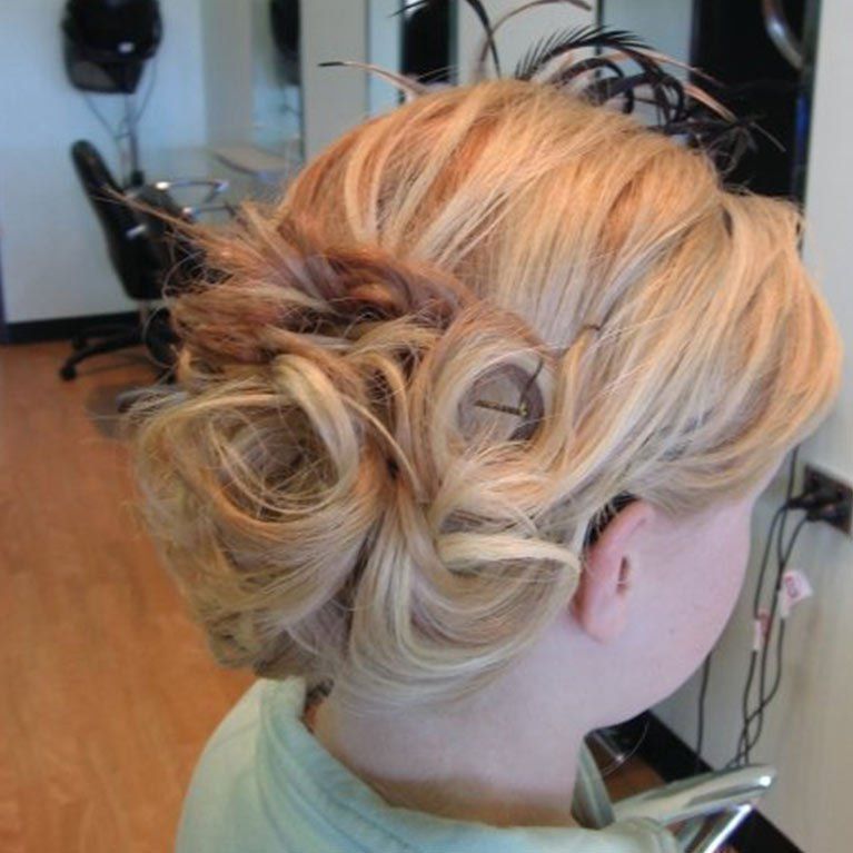 A woman has her hair in a bun with feathers in it