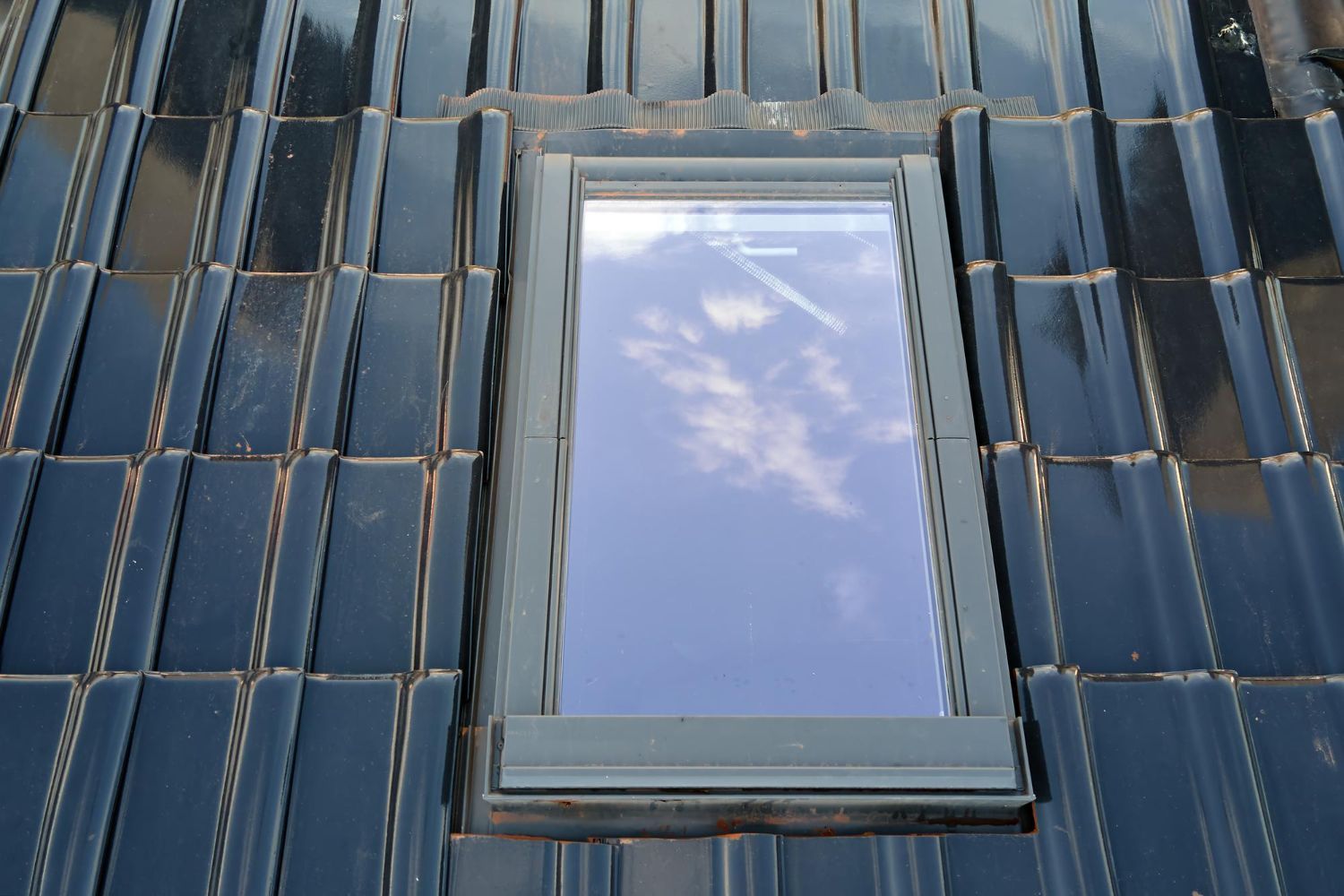 A skylight on the roof of a building with a blue sky reflected in it.