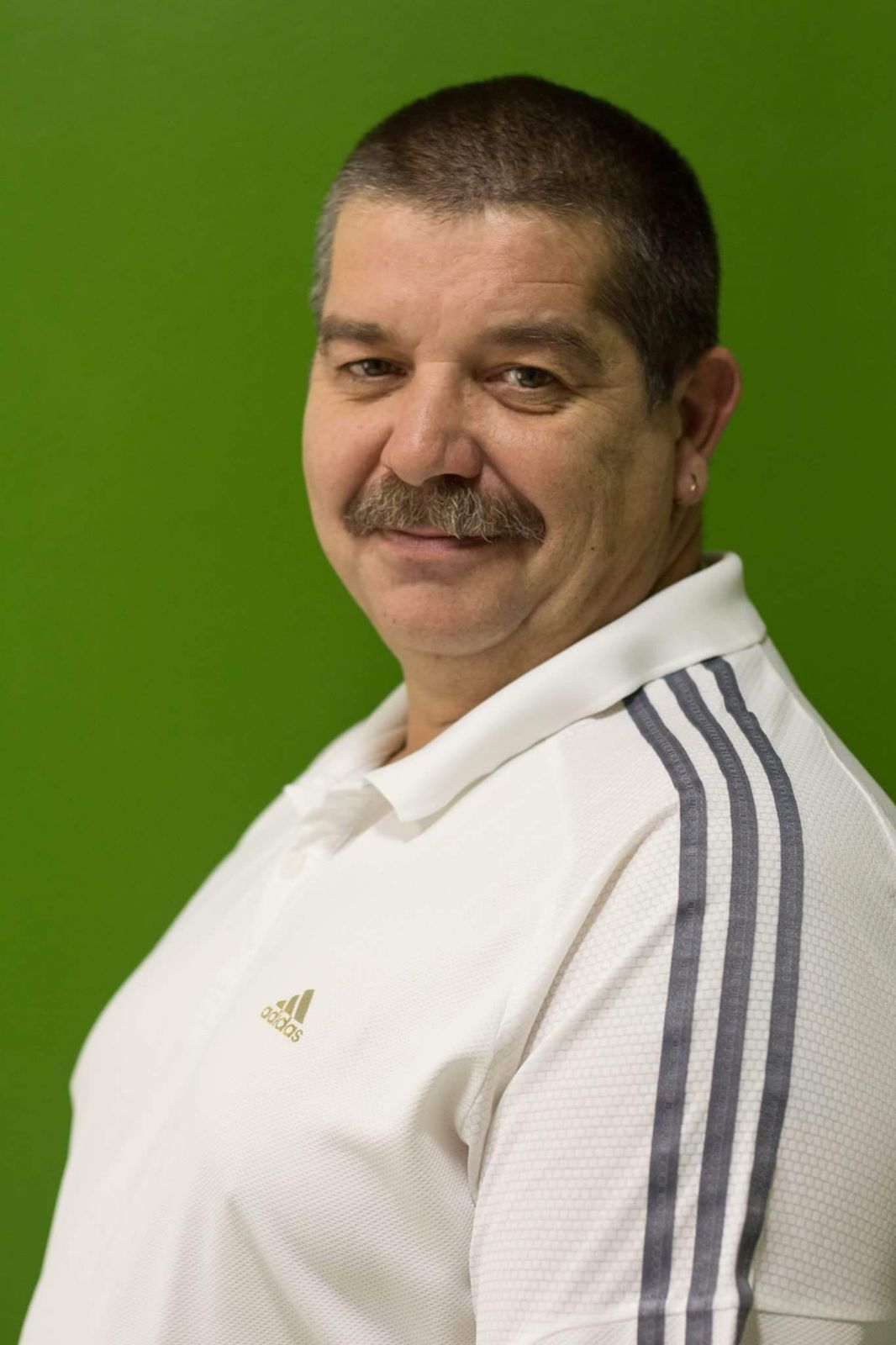 Ein Mann mit Schnurrbart trägt ein weißes Adidas-Shirt