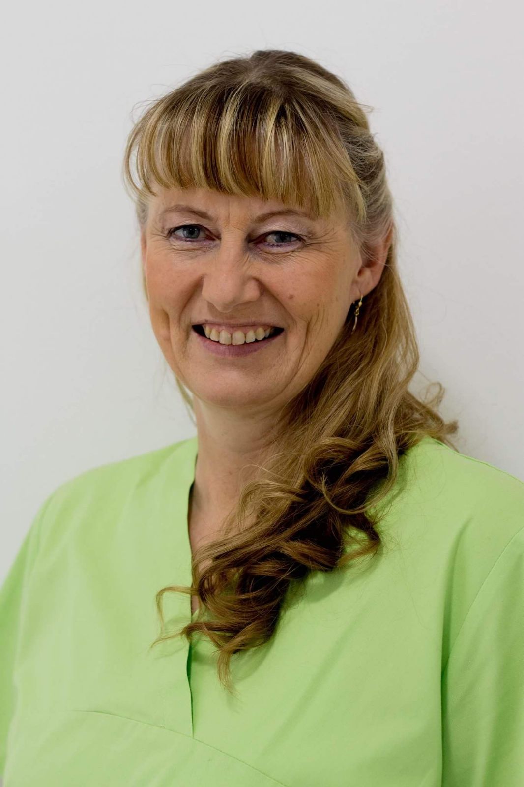 Eine Frau im grünen OP-Kittel lächelt in die Kamera.