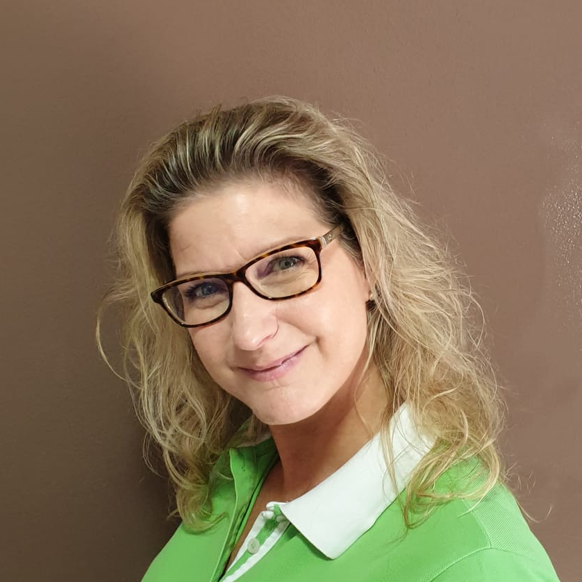 Eine Frau mit Brille und grünem Hemd lächelt