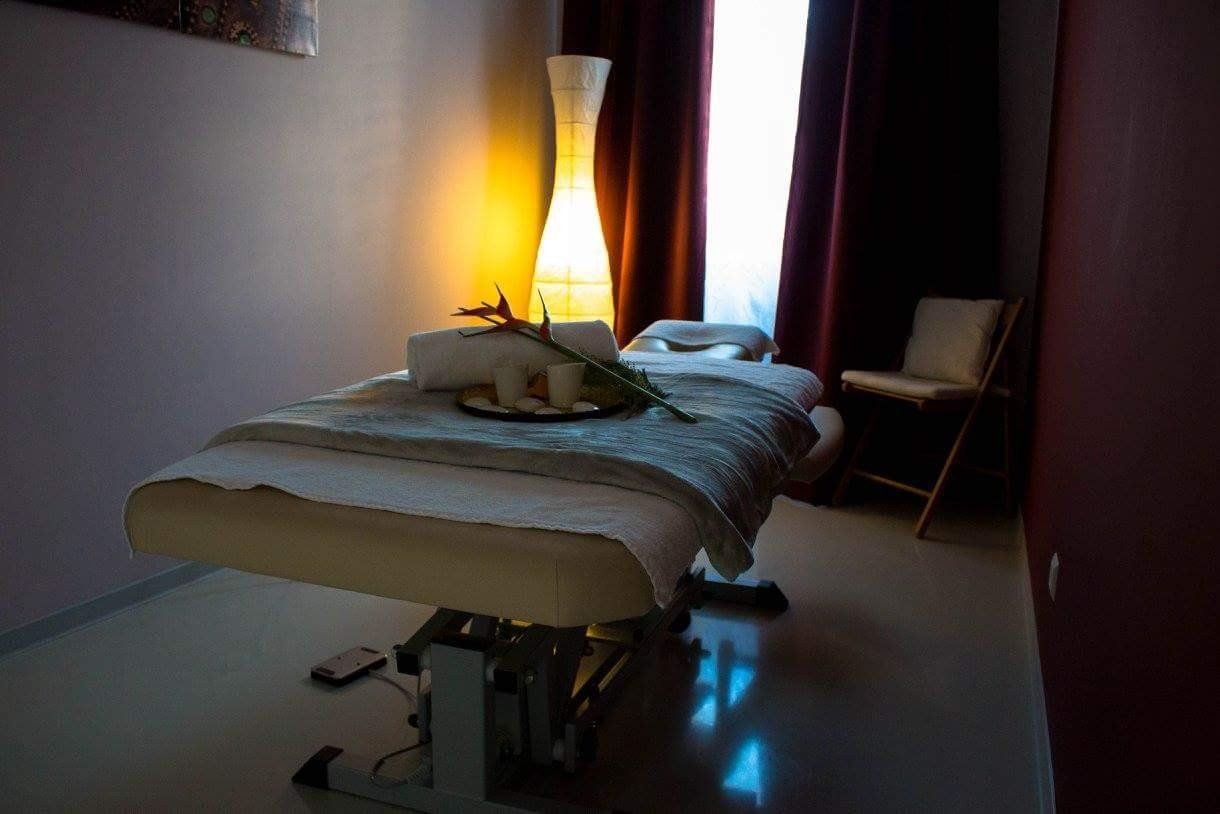 Ein Massagetisch in einem dunklen Raum mit einer Blume darauf.