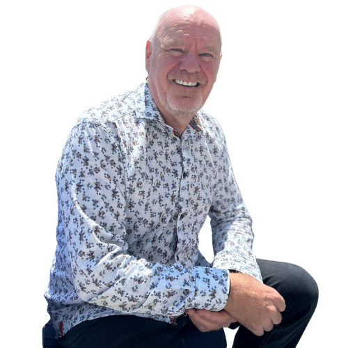 A man in a floral shirt is sitting down and smiling.
