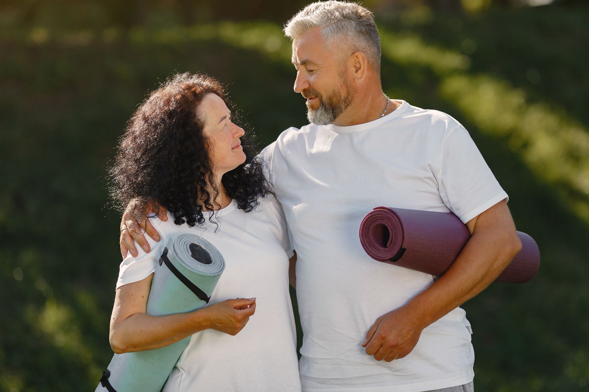 A man and a woman are standing next to each other holding yoga mats.