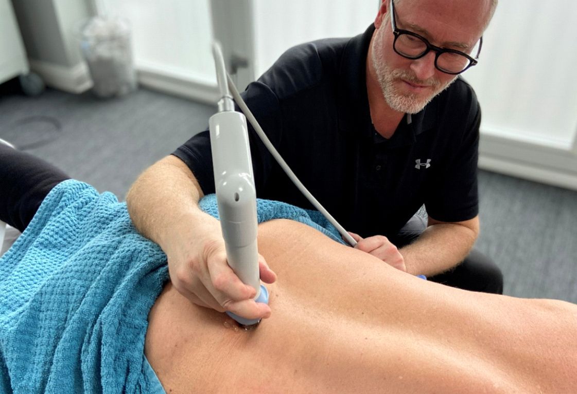 A man is using an ultrasound on a patient 's back.