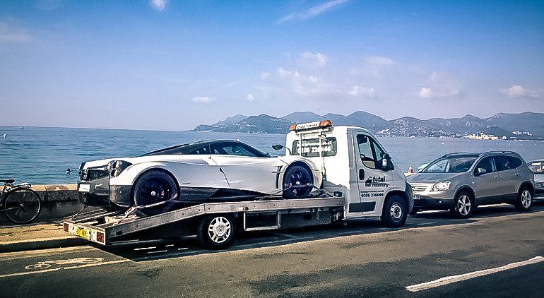 A white car is being towed by a tow truck.