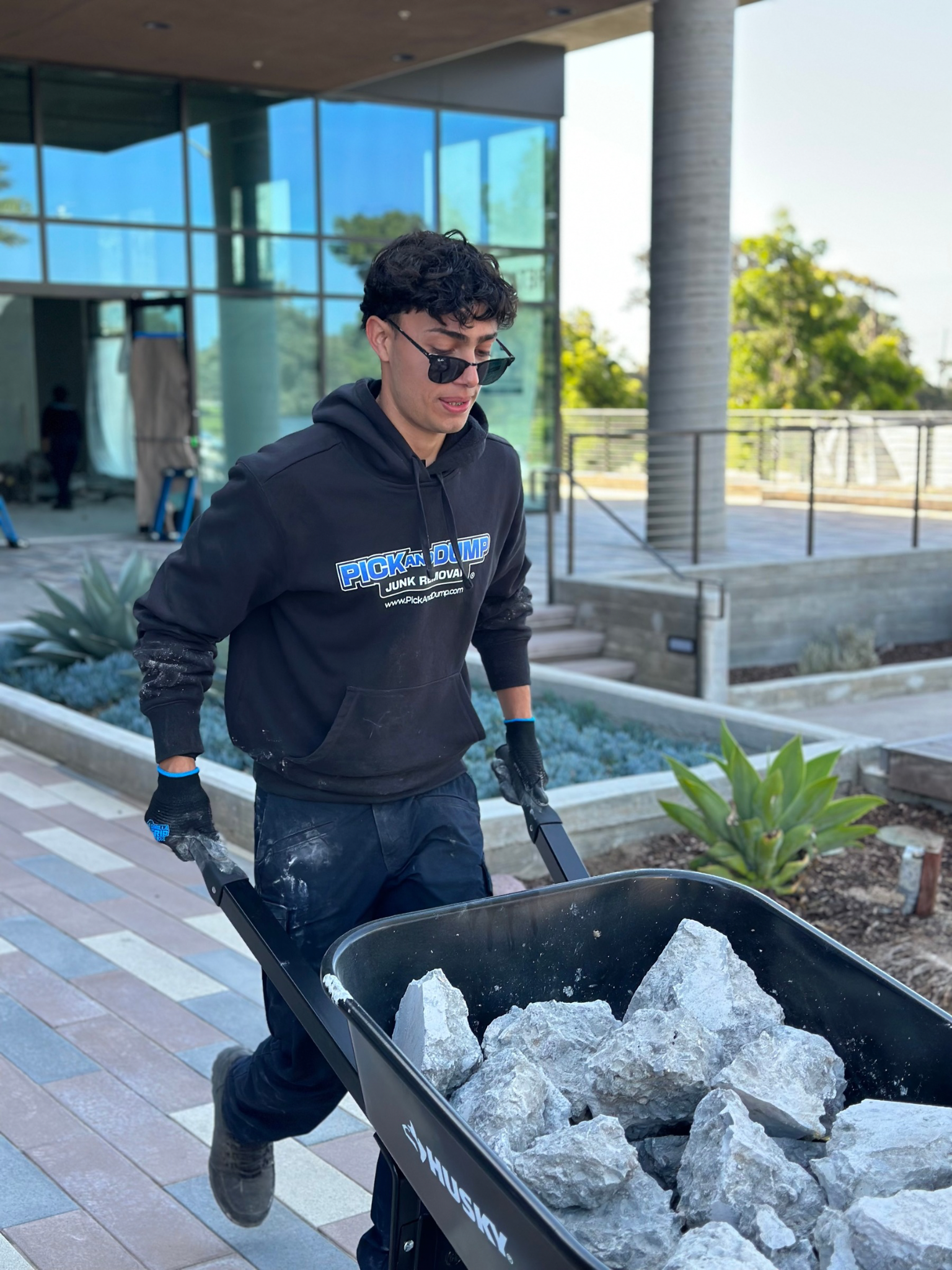 A crew member is pushing a wheelbarrow full of concrete debris.