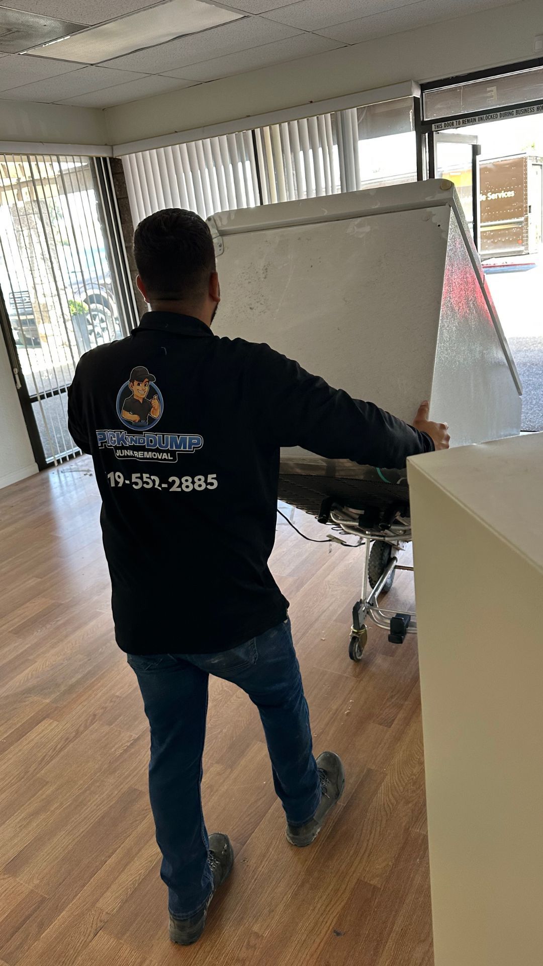 A man is carrying a refrigerator in a room.