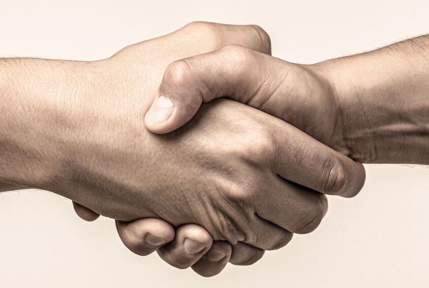 A close up of two people shaking hands on a white background.