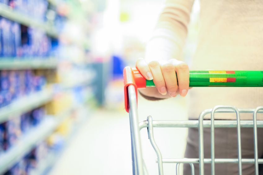 A woman is pushing a shopping cart in a store.