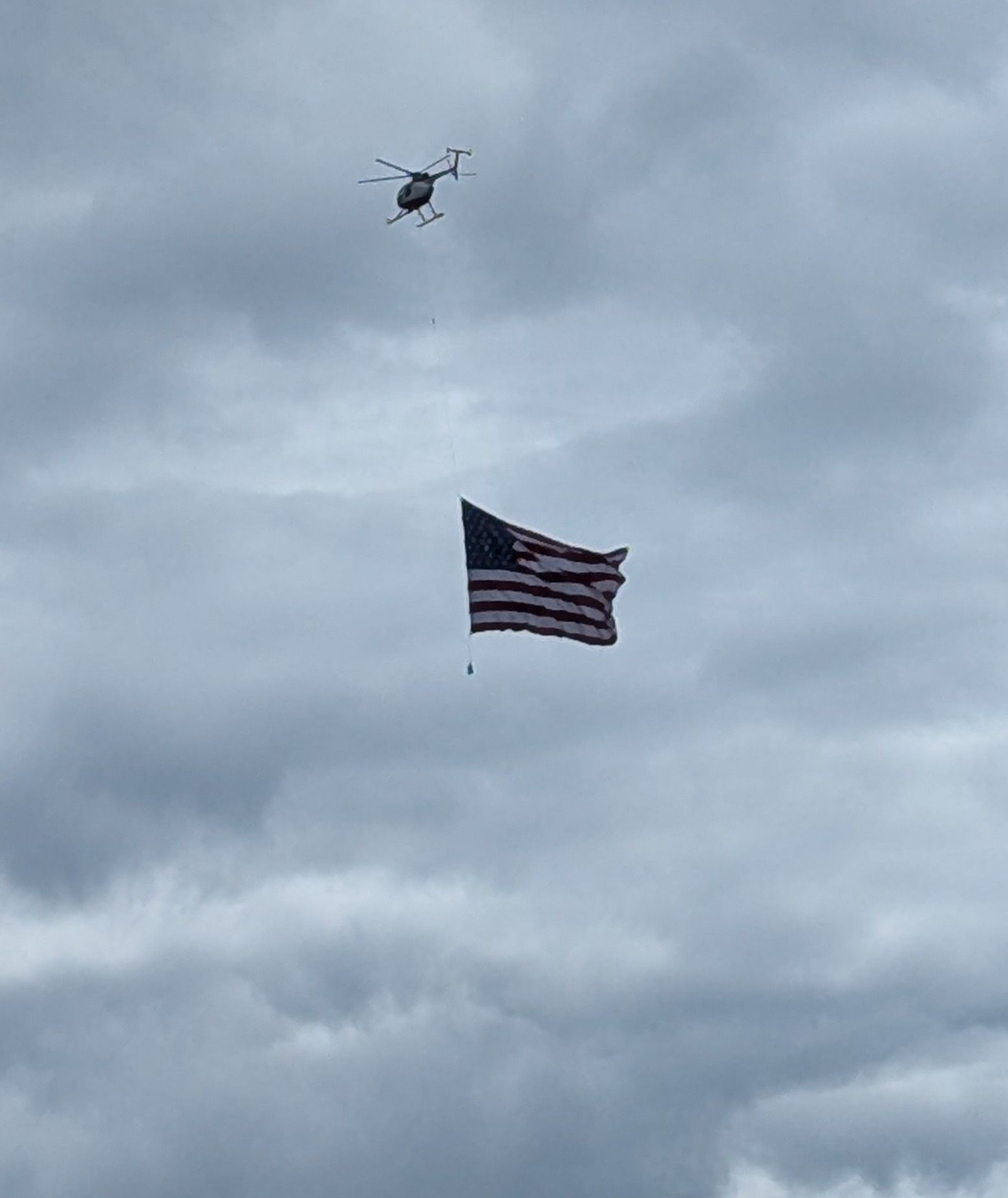A helicopter is flying over an american flag in the sky.