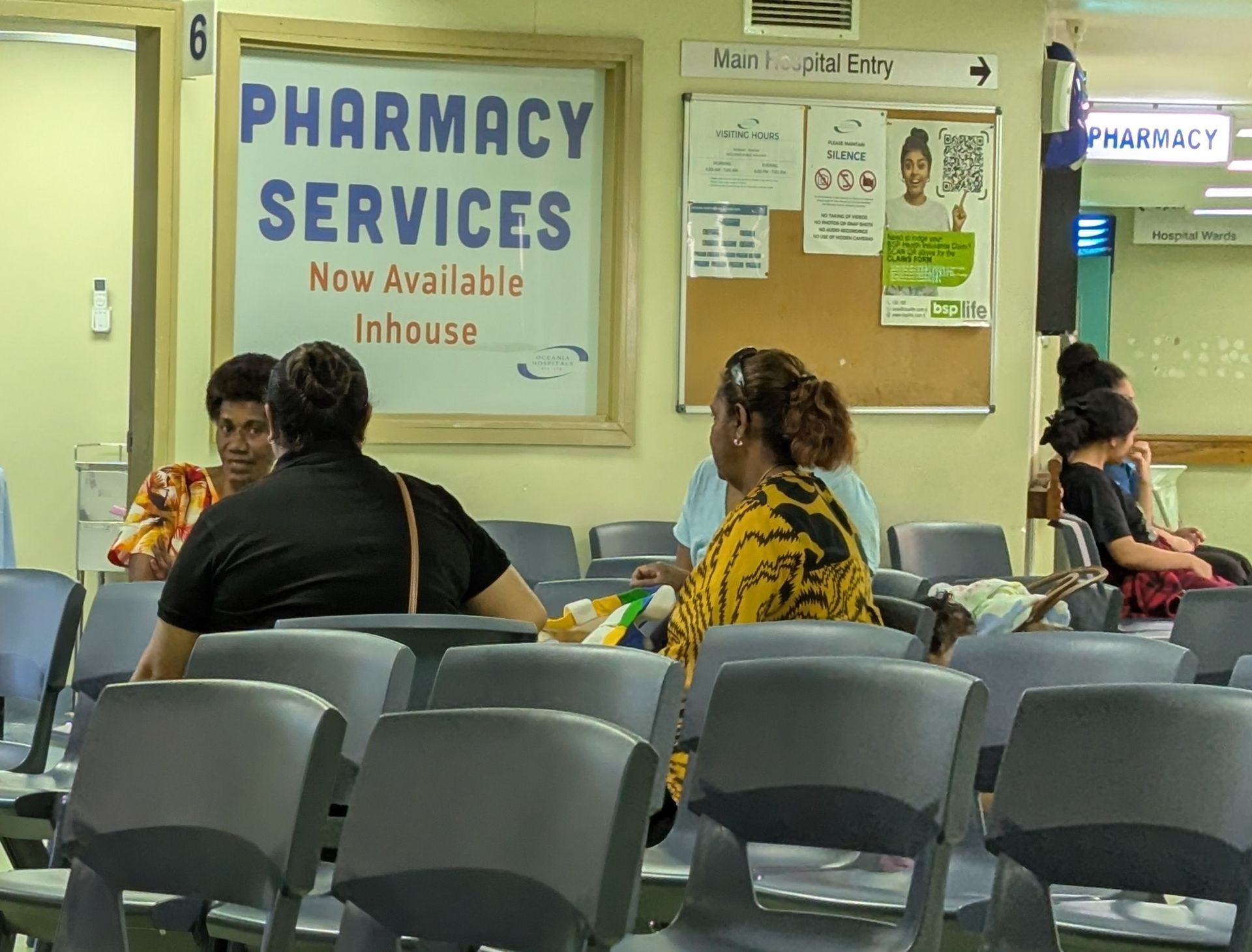 Children playing near a boat, next to a wooden building. One child jumps, others sit or stand.