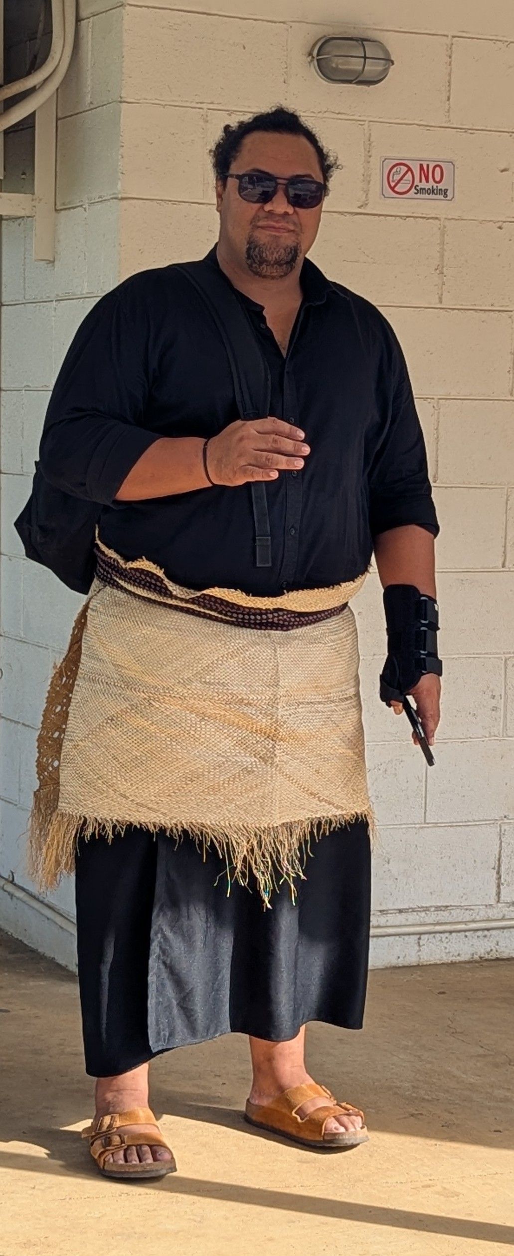 Children playing near a boat, next to a wooden building. One child jumps, others sit or stand.