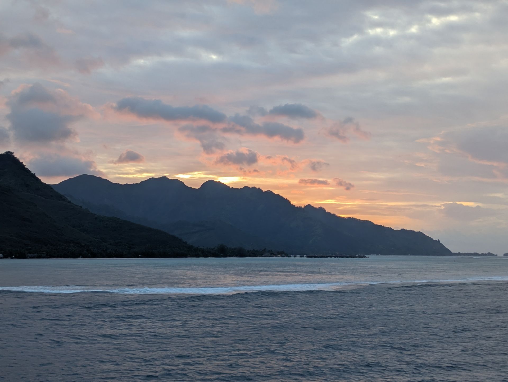 Two kayaks on a calm lake, with mountains and cloudy sky in the background.