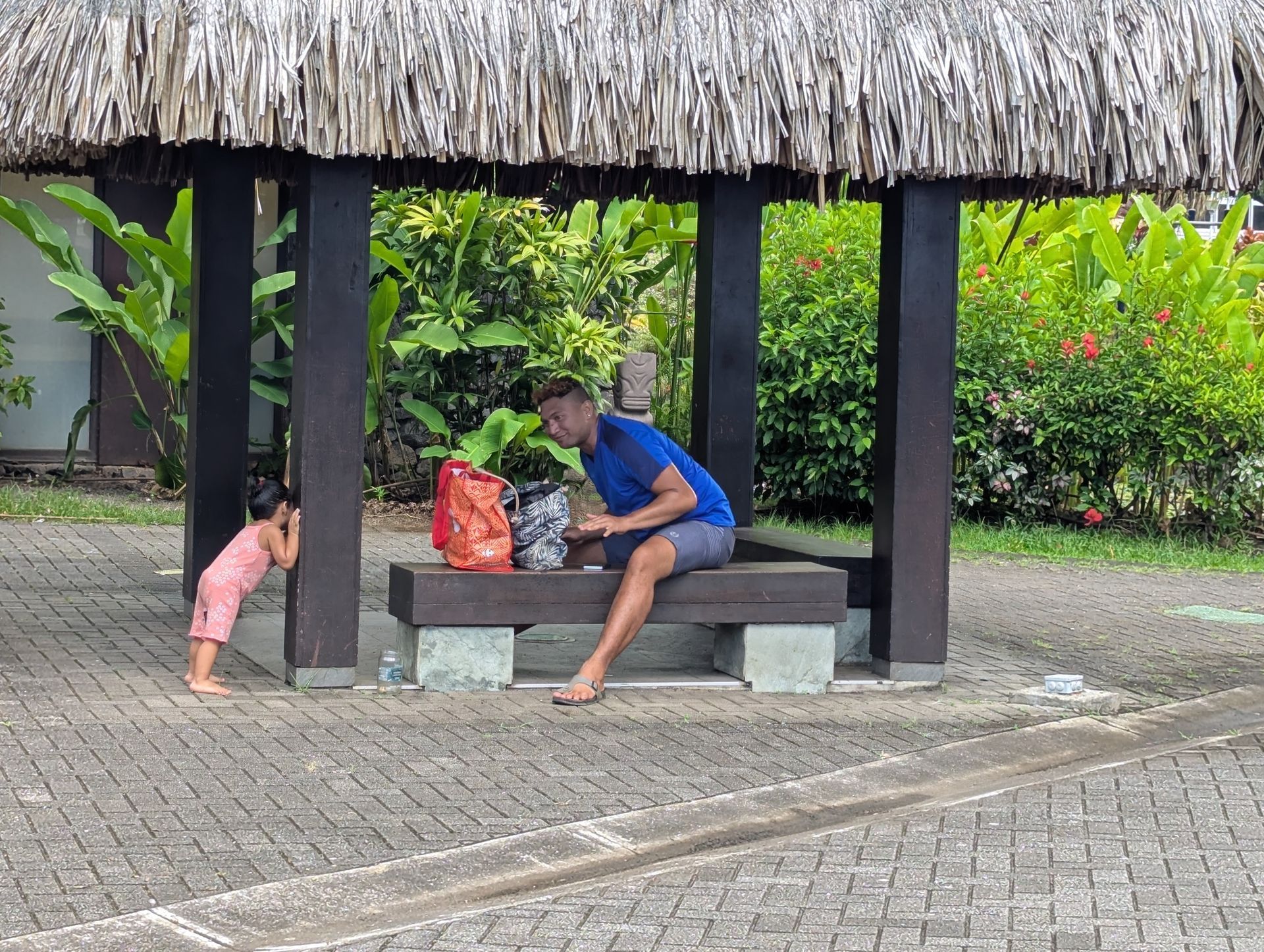 Children playing near a boat, next to a wooden building. One child jumps, others sit or stand.