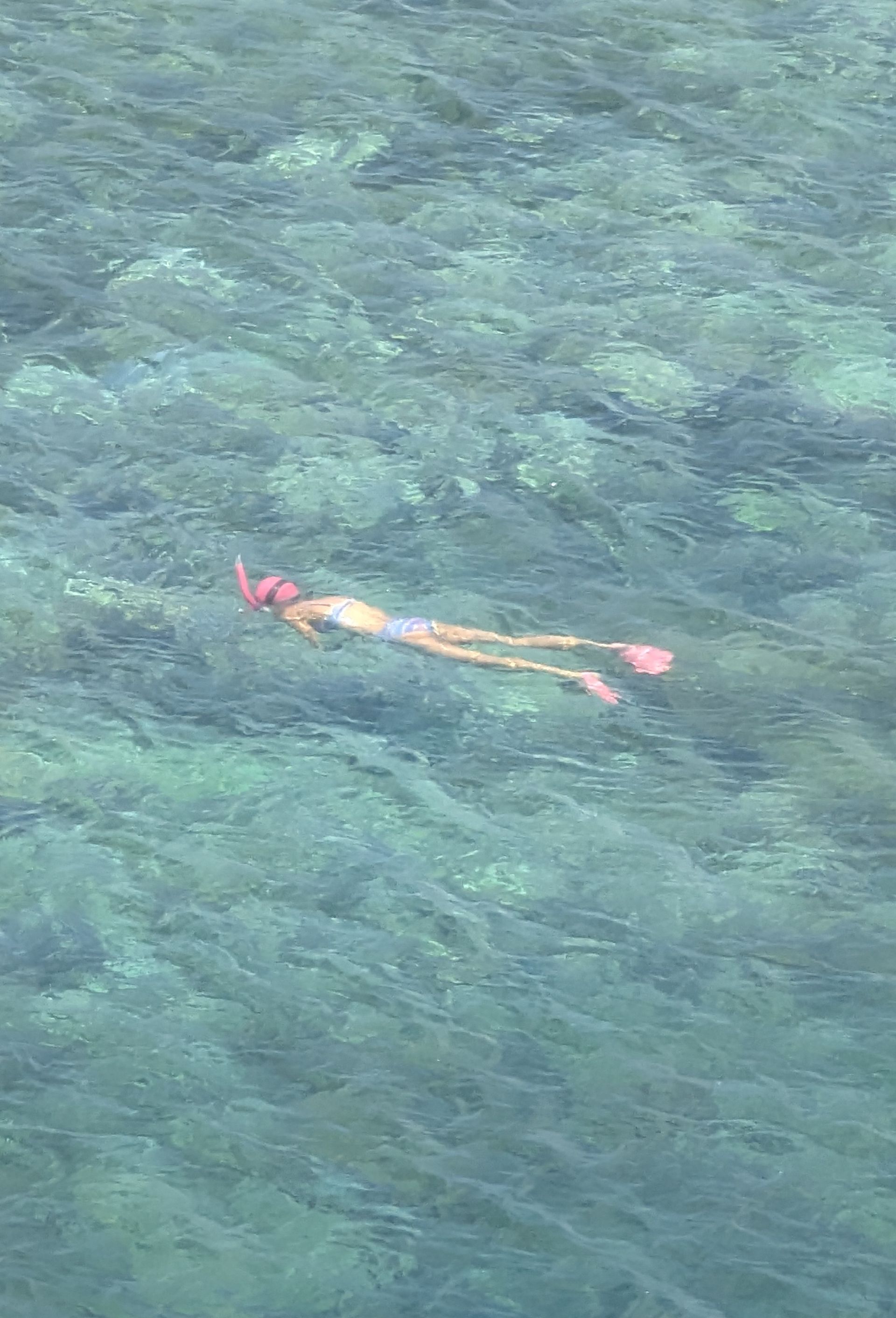 Two people paddle a wooden boat on a body of water.