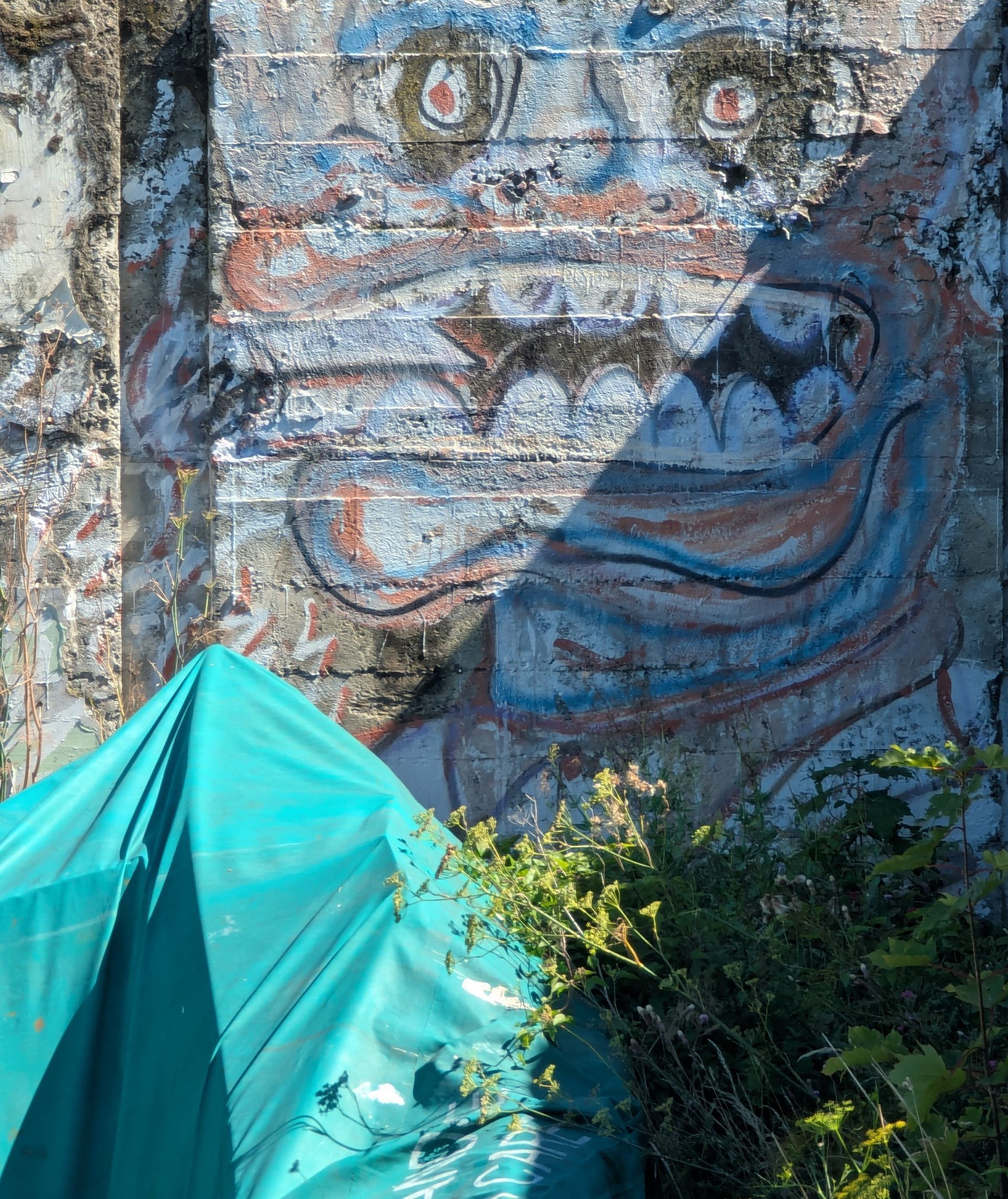 Children playing near a boat, next to a wooden building. One child jumps, others sit or stand.
