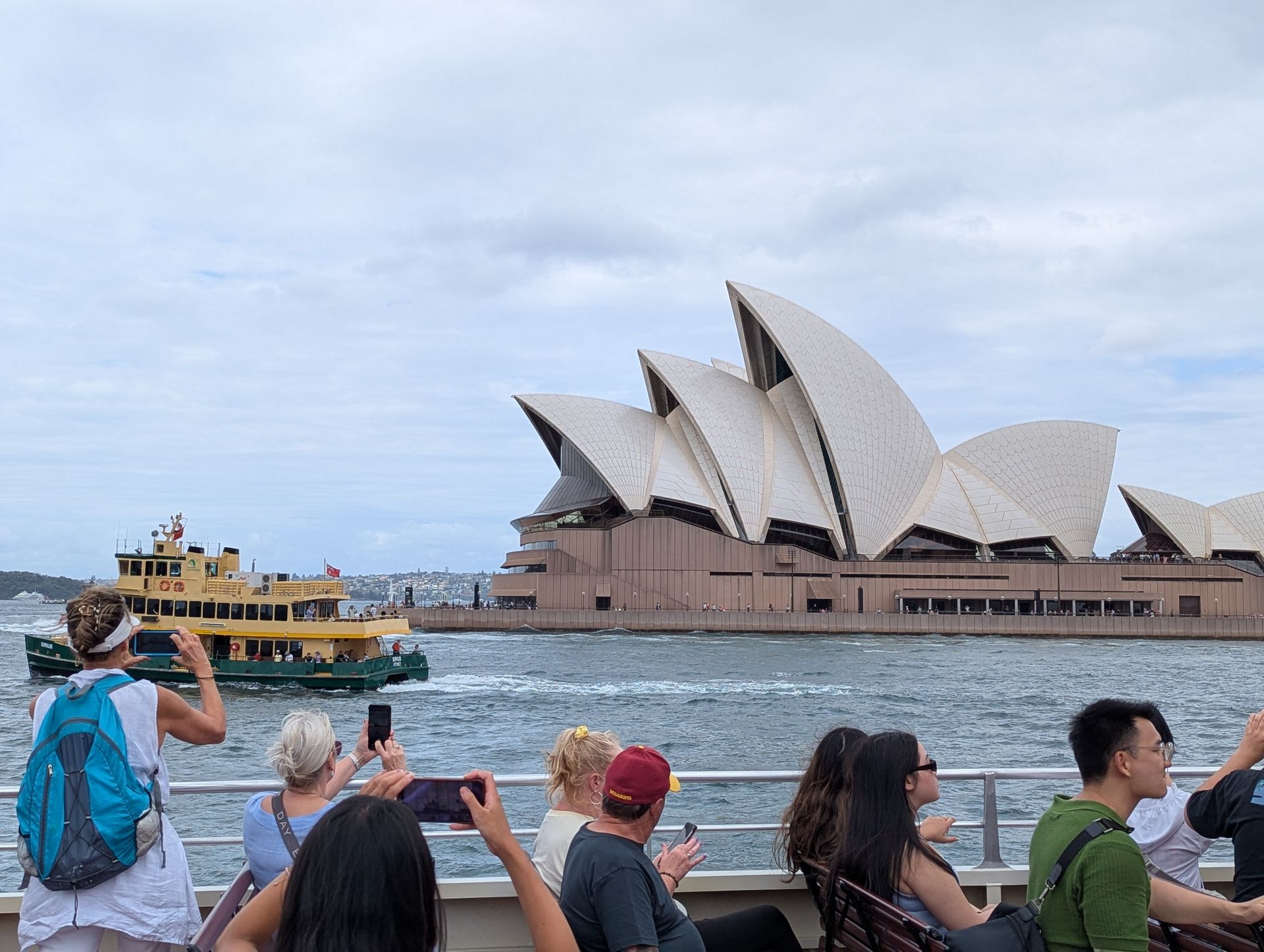 Children playing near a boat, next to a wooden building. One child jumps, others sit or stand.