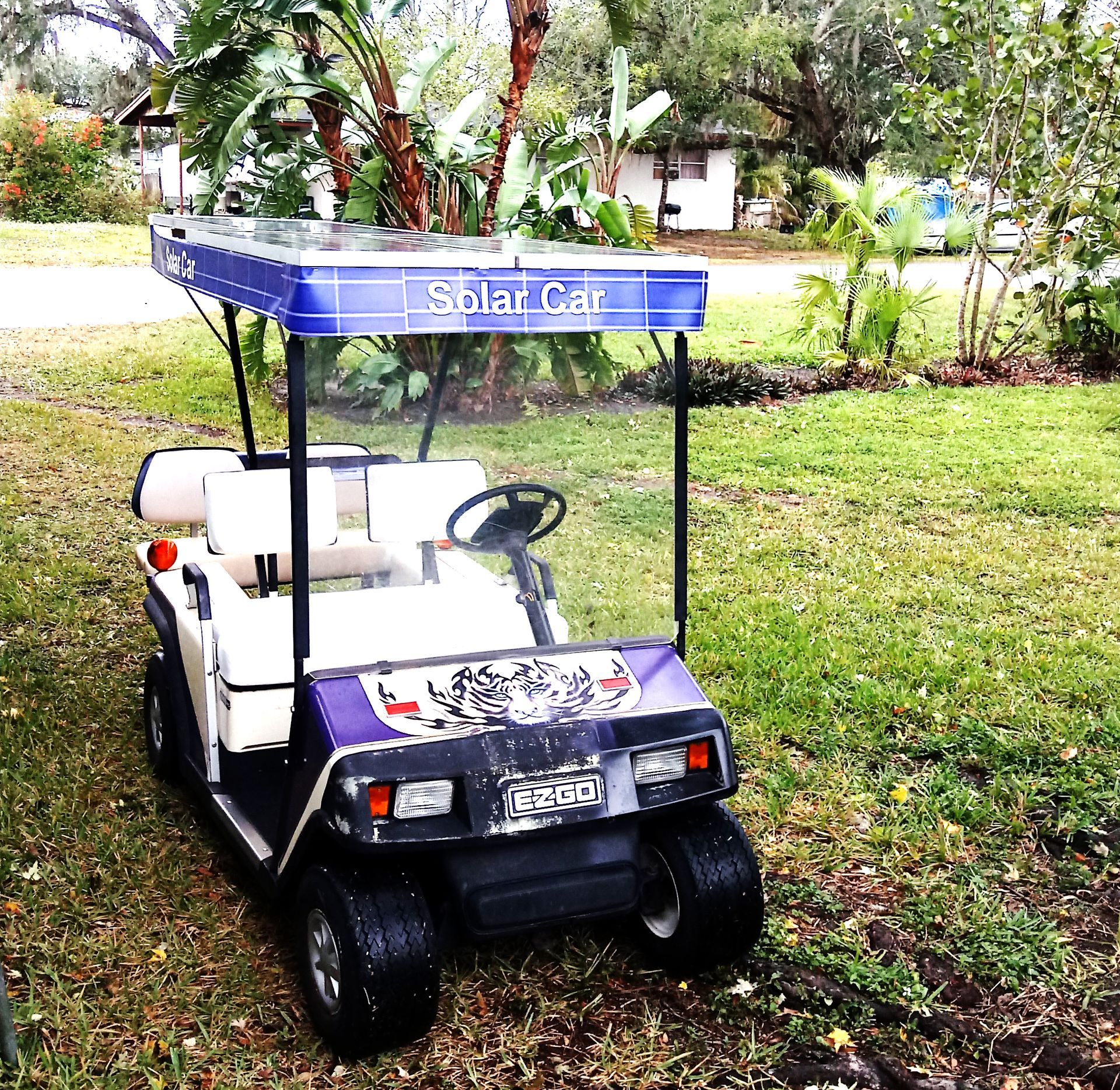 A golf cart with a blue canopy that says solar gaz