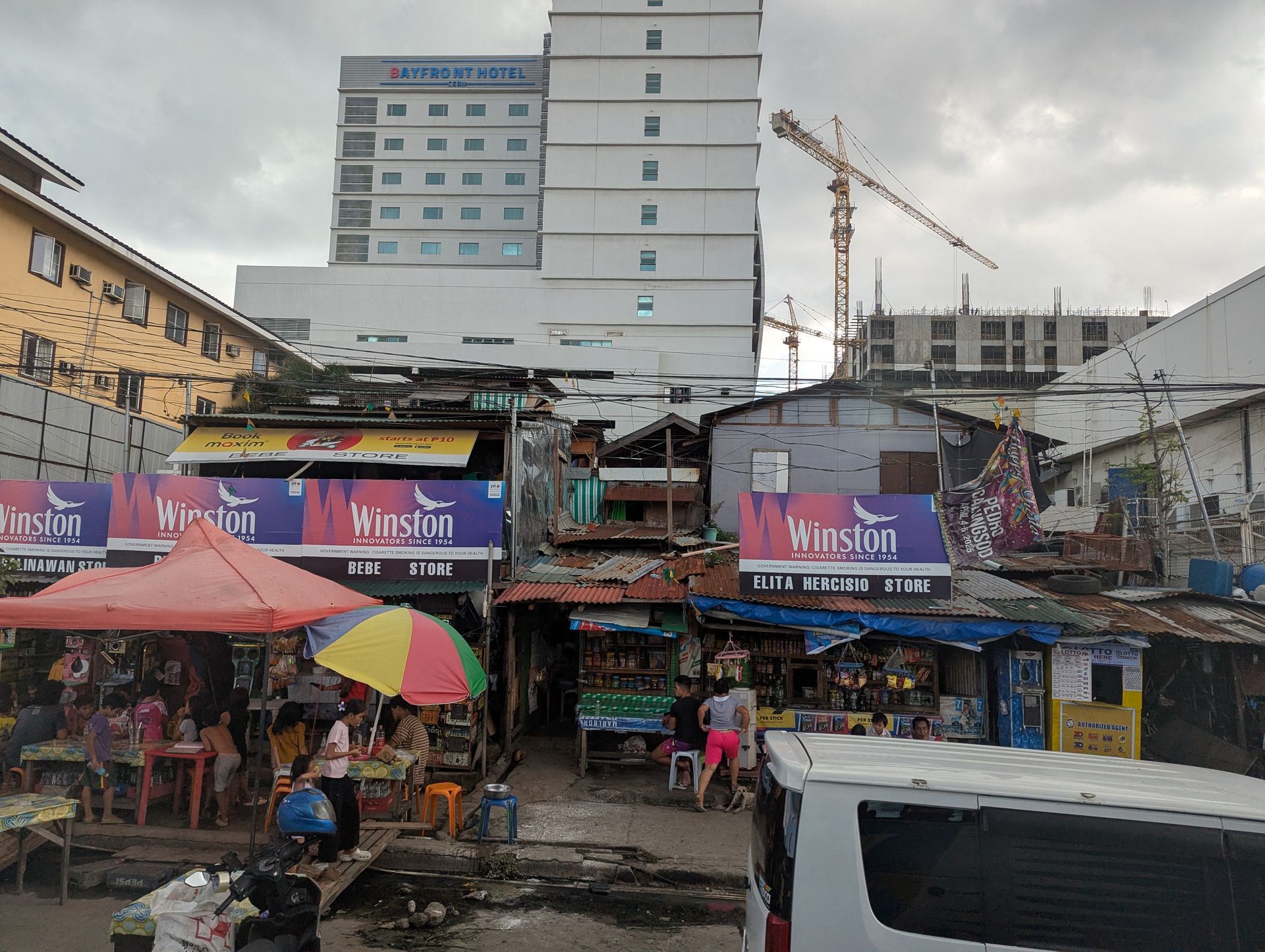 Street scene with vendors, umbrellas, and tall buildings in the background under an overcast sky.