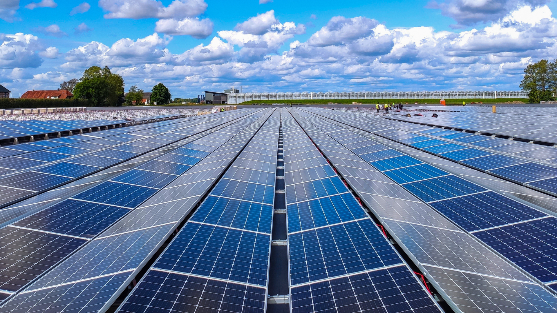 There are many solar panels on the roof of a building.