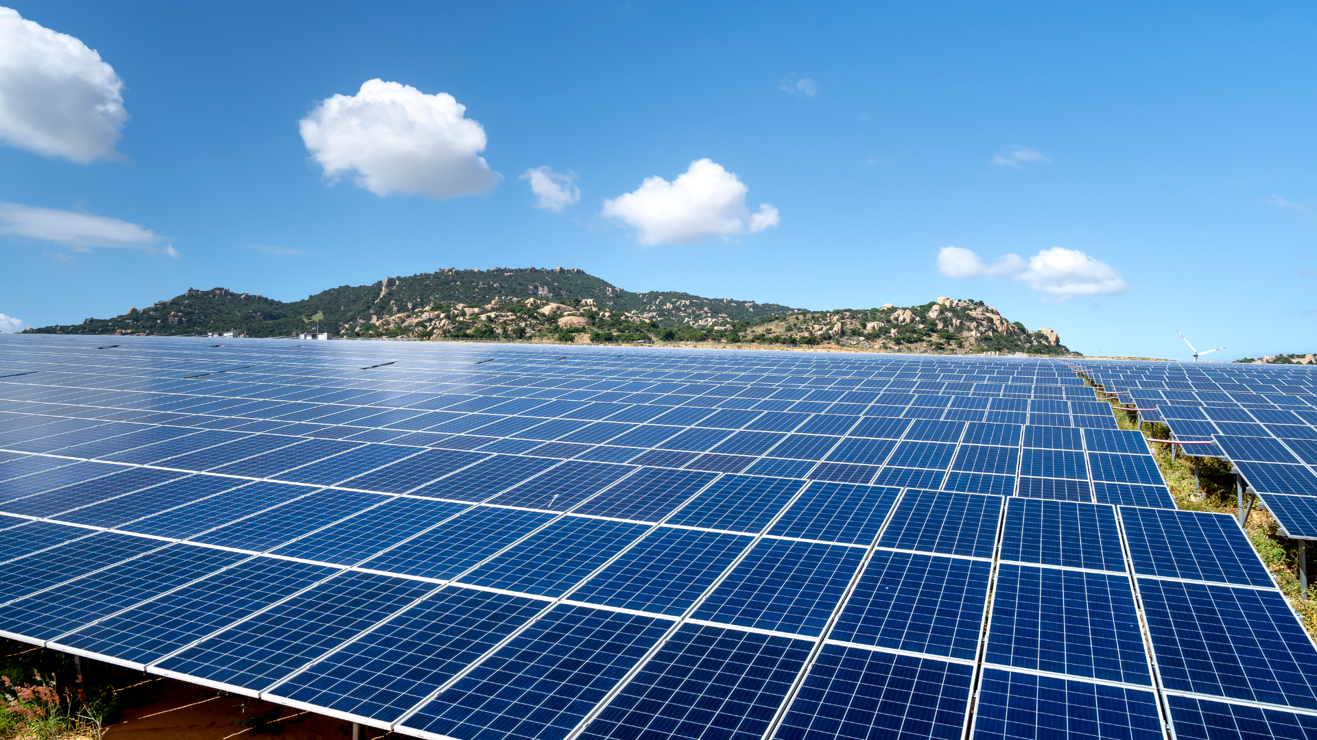 A field of solar panels with mountains in the background