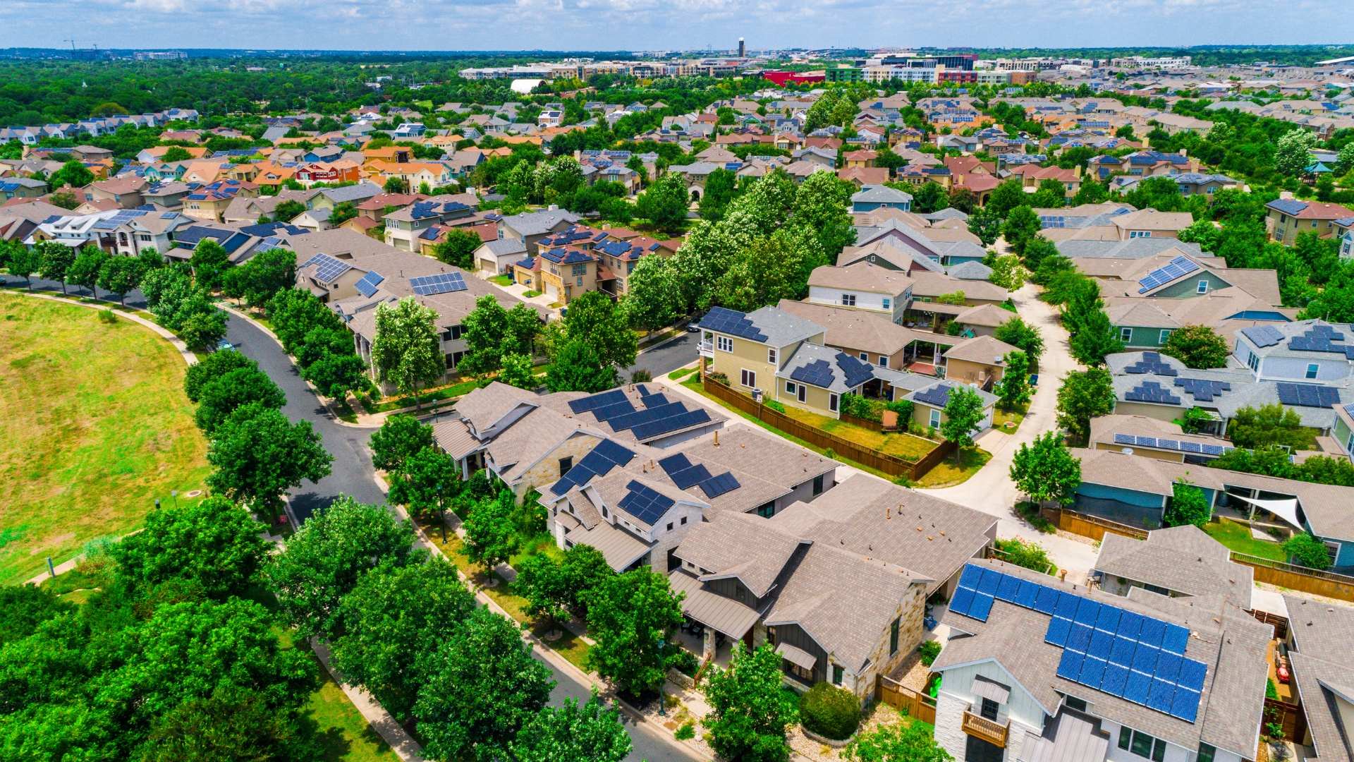 An aerial view of a residential neighborhood with solar panels on the roofs.