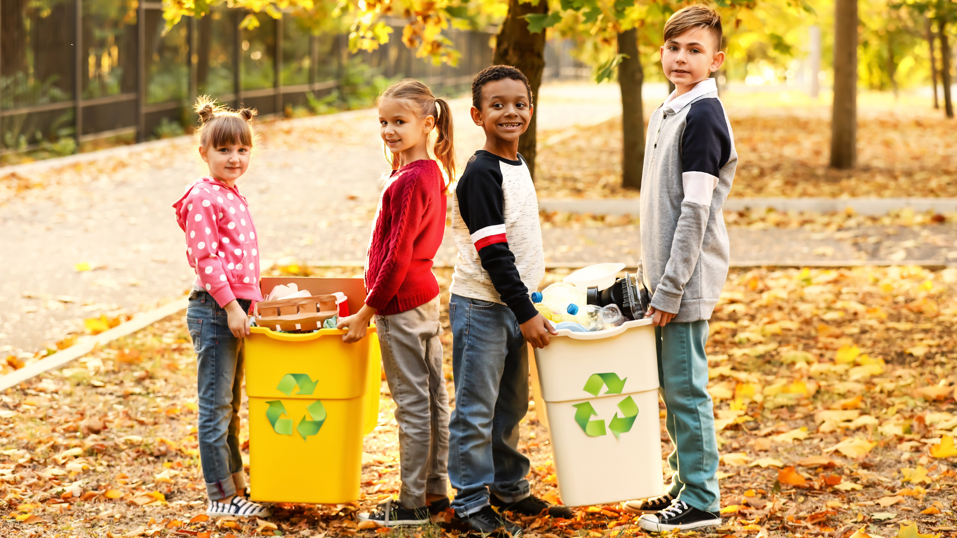 A group of children are standing next to each other holding recycling bins.