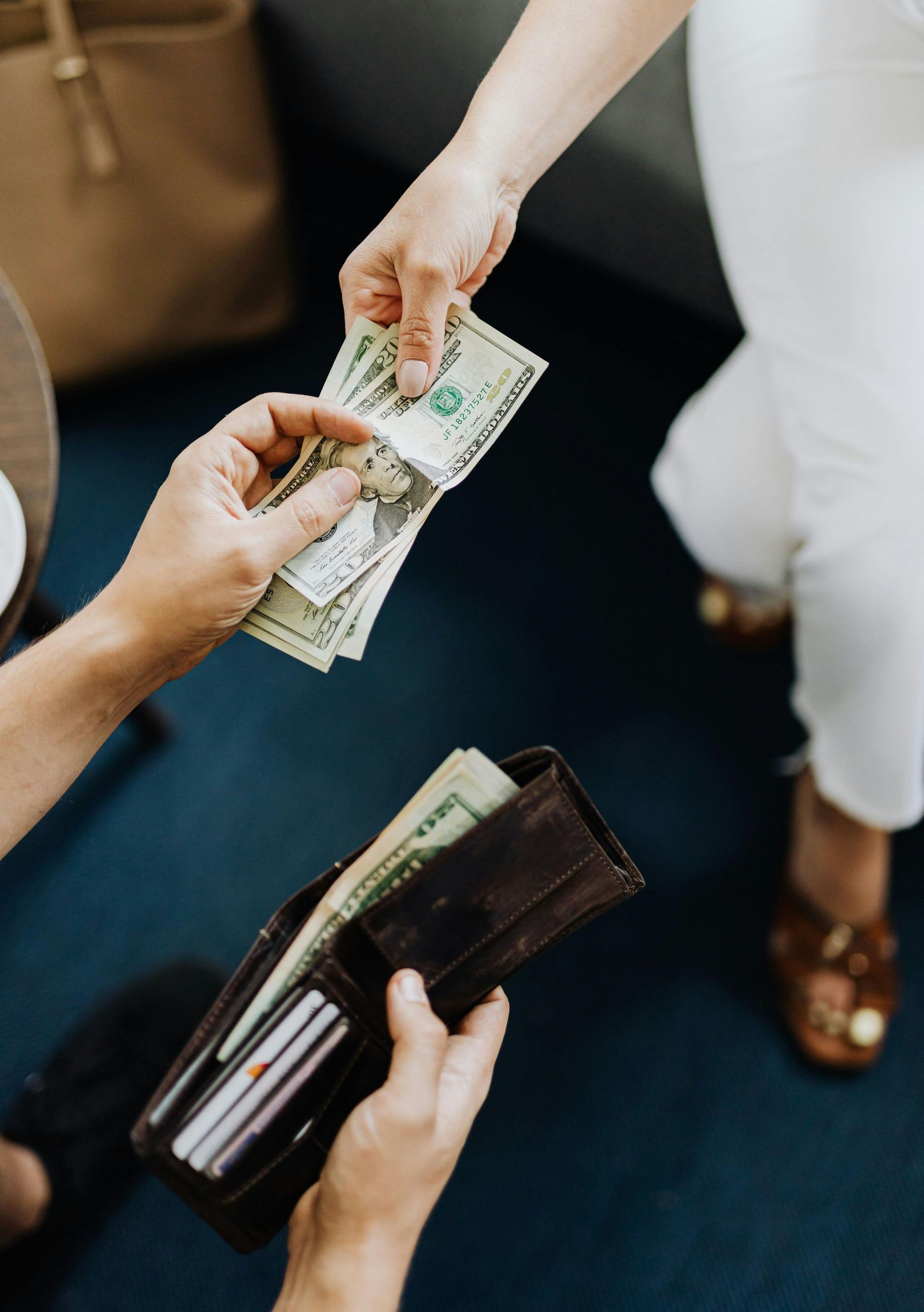 A woman is handing a wallet full of money to another woman.