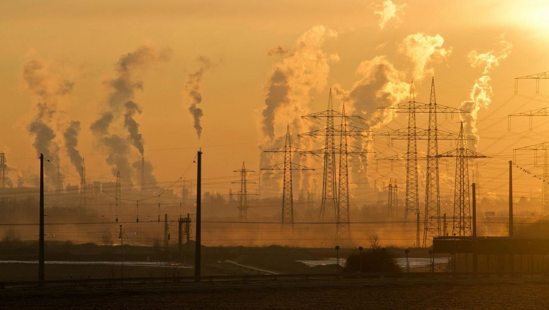 A factory with smoke coming out of the chimneys at sunset.