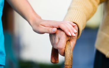 Hand on seniors hand over cane