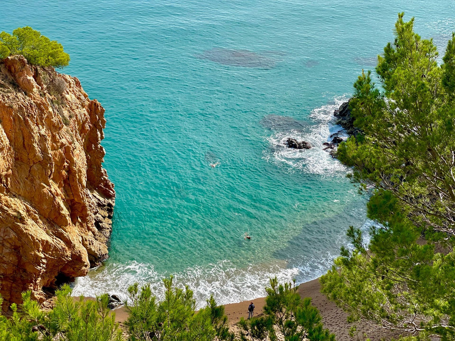 A view of a beach from a cliff overlooking the ocean.