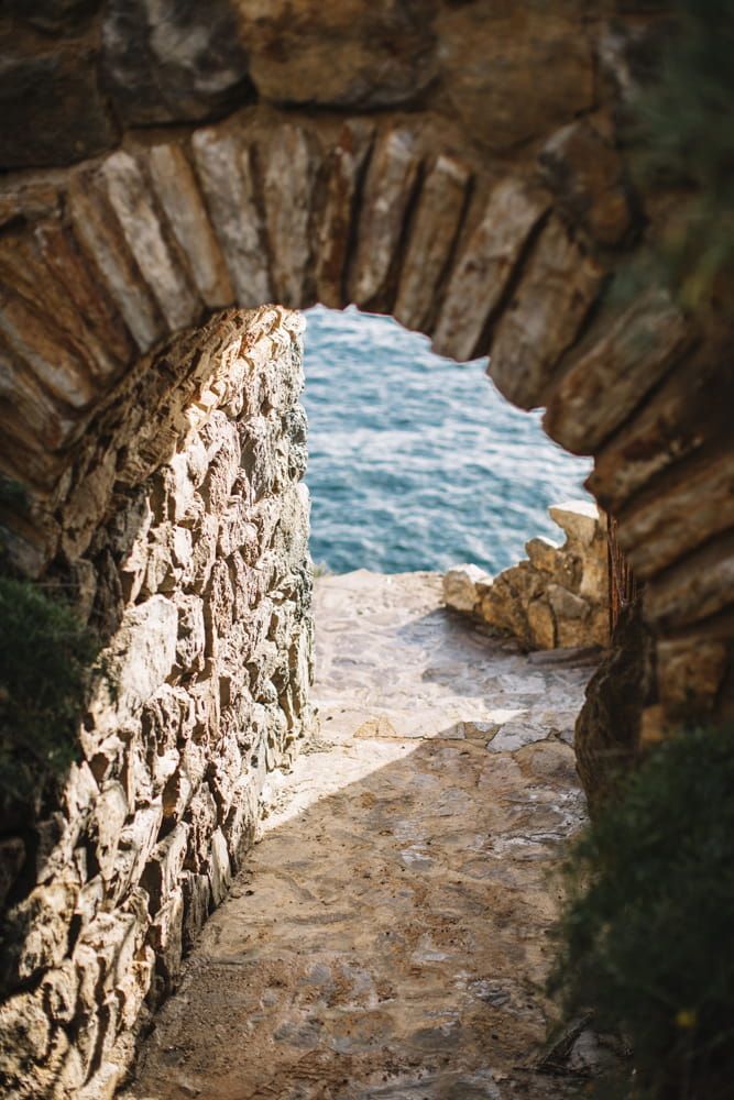 There is a stone archway leading to the ocean.