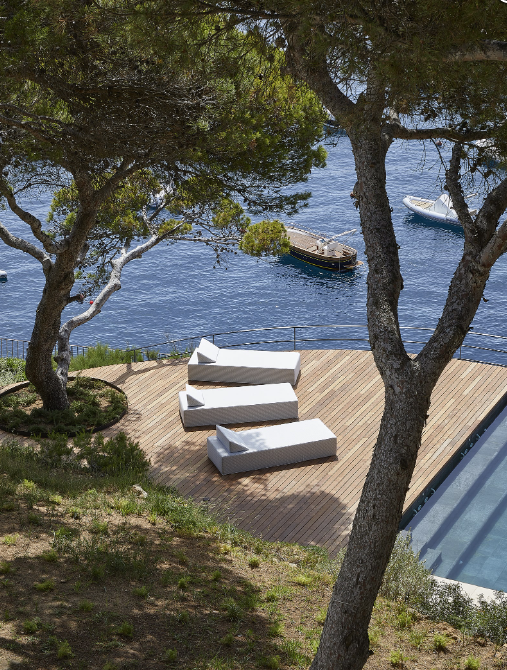 A row of lounge chairs on a deck overlooking the ocean