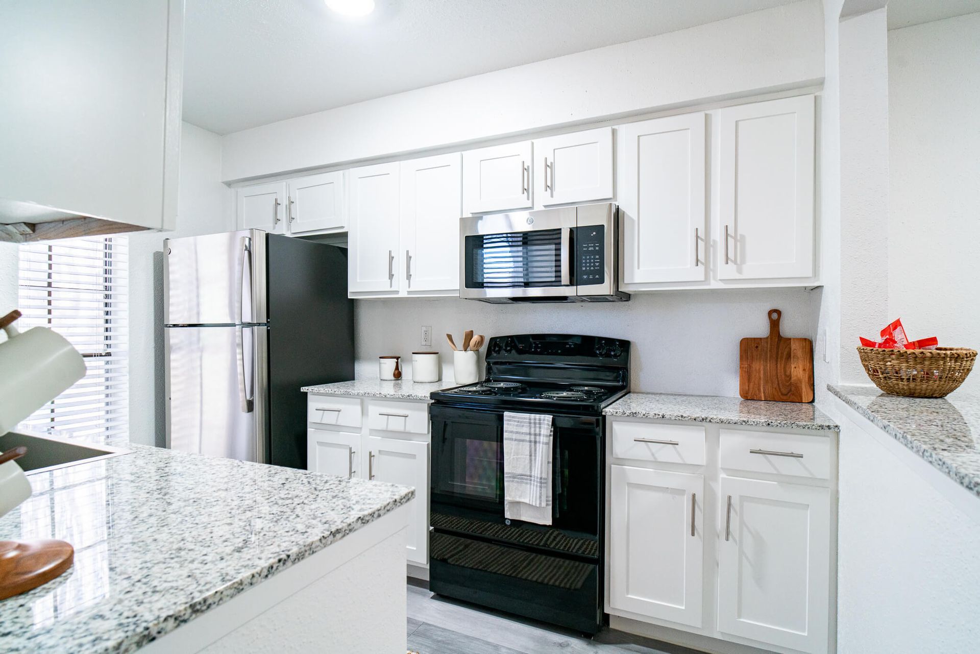 Bright kitchen with white cabinets, granite countertops, and stainless steel appliances.