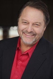 A man in a suit and red shirt is smiling for the camera.